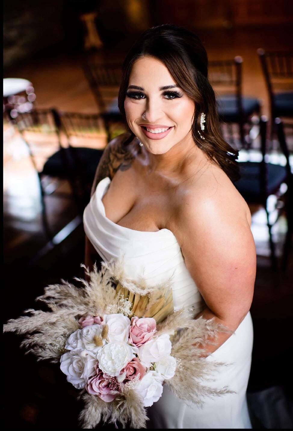 May include: A bouquet of dried flowers with white and pink roses and beige pampas grass.